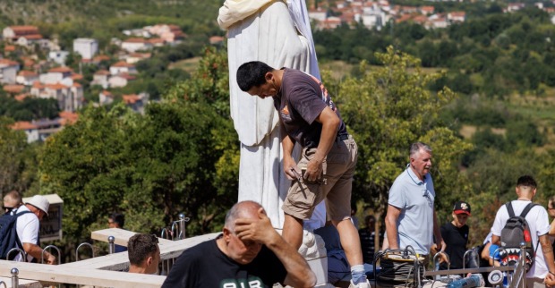 Mitarbeiter reinigen eine Marienstatue auf dem Erscheinungsberg in Medjugorje, nachdem der berühmte Wallfahrtsort Ziel eines Brandanschlags und von Vandalismus wurde.