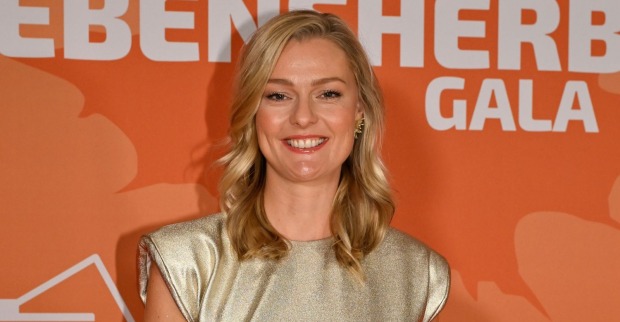 Miriam Höller lächelt bei einem öffentlichen Event in einem goldenen Kleid. Die ehemalige Stuntfrau spricht zehn Jahre nach ihrem Schicksalsjahr über Verlust, Neuanfang und ihr neues Glück.