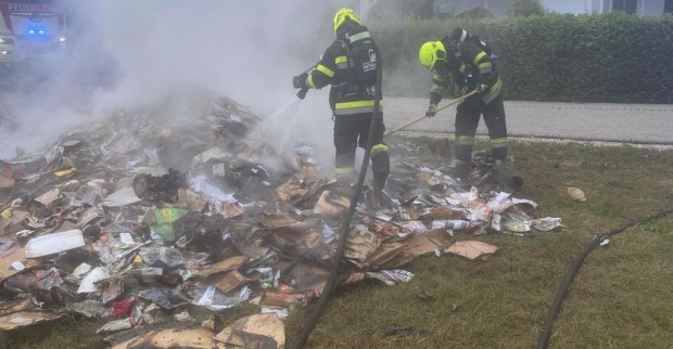 Einsatzkräfte der Feuerwehr löschen brennenden Papiermüll auf der Straße