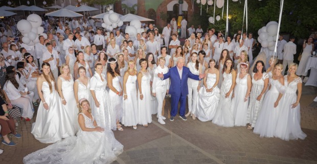 Robert Rogner in einem blauen Anzug, umringt von Frauen in weißen Brautkleidern