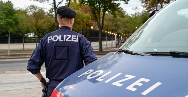 Polizist steht neben Polizeiauto im Einsatz während Fahndung nach vermisstem Mädchen im Trillerpark Wien