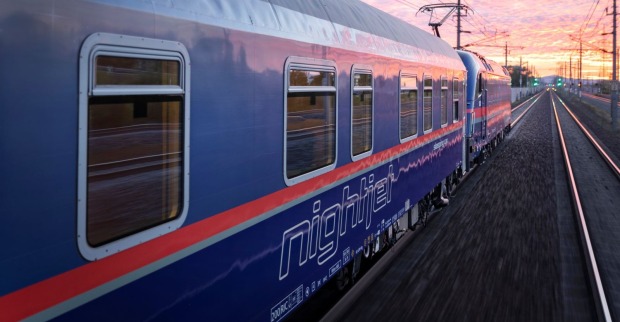 Ein ÖBB-Nachtzug fährt durch eine ländliche Region auf der Weststrecke zwischen Amstetten und Linz