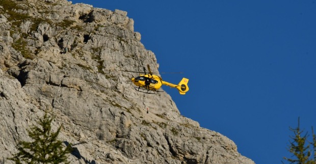 Ein gelber Rettungshubschrauber bei einem Einsatz in den Bergen.