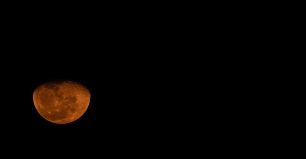 Partielle Mondfinsternis mit rötlichem Schimmer am morgendlichen Dämmerungshimmel
