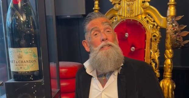 Roland „Crazy Cheese“ Ludomirska aus „Villa der Versuchung“ sitzt vor einem goldenen Thron und einer großen Champagnerflasche.
