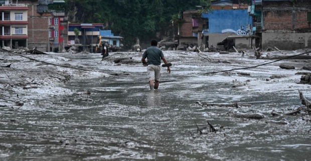 Mann geht durch Schlamm und Geröll nach der verheerenden Sturzflut in Nepal.