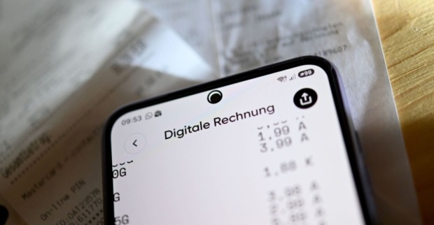 Digitale Rechnung auf einem Smartphone vor gedruckten Rechnungen