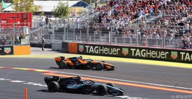 Formel-1-Boliden von Mercedes und McLaren auf dem Stadtkurs vor einer voll besetzten Tribüne.
