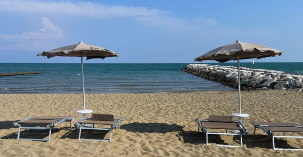 Strand von Caorle mit Liegen und Sonnenschirmen am Meer.