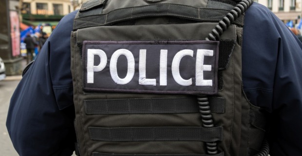 "POLIZEI"-Schild auf der Rückseite einer taktischen Weste eines französischen Polizisten in einer Straße von Paris.