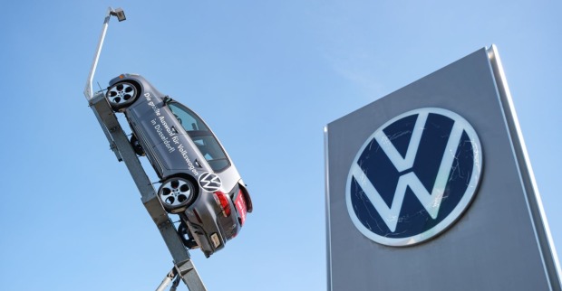 VW Logo neben einem Volkswagen Auto. Der Konzern will die Automarke Seat laut einem Bericht bis Ende 2029 einstellen.