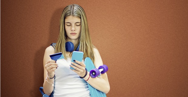 Mädchen mit Kopfhörern hält ein Smartphone in den Händen. Neben ihr sind ein Rucksack und ein Skateboard zu sehen.