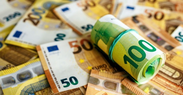 Gerollter 100-Euro-Schein auf mehreren Euro-Banknoten als Symbolbild für die Bargeld-Obergrenze 2027 in Österreich.