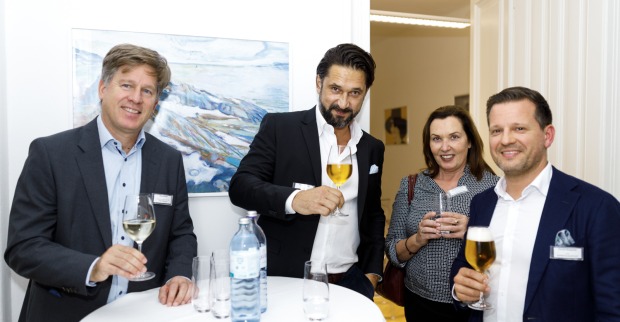 Vier Personen im Business-Outfit mit Gläsern in ihren Händen