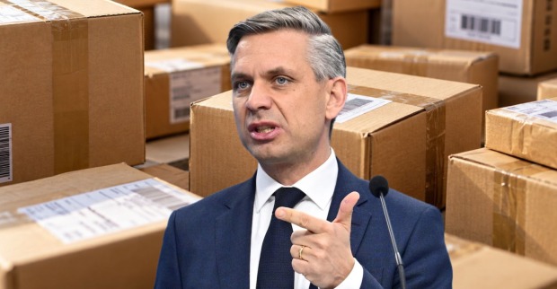 Fotomontage von Wirtschaftsminister Wolfgang Hattmannsdorfer vor zahlreichen Versandpaketen. Er spricht über die Paketsteuer und mögliche neue Regeln für Lieferungen von Temu und Shein.