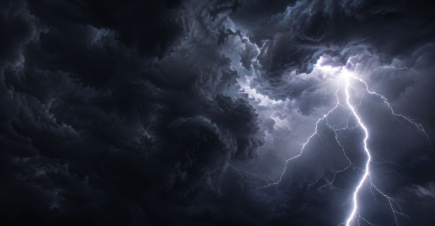 Dunkle Gewitterwolken und ein Blitz am Himmel.