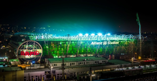 Das grün beleuchtete Allianz Stadion des SK Rapid Wien bei Nacht. Die Heimstätte der Hütteldorfer mit dem großen Rapid-Schriftzug.