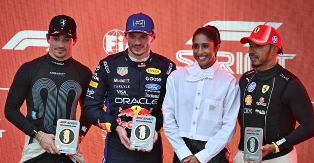 Max Verstappen mit Siegerpokal beim Singapur Sprint 2026, gemeinsam mit Charles Leclerc und Lewis Hamilton bei der Siegerehrung.