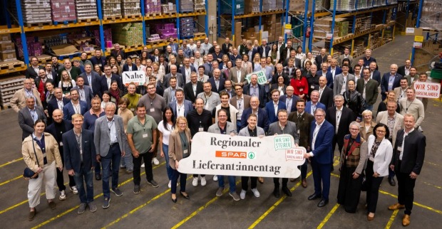 Eine Menschengruppe blickt nach oben, ganz vorne ist ein Schild zu sehen