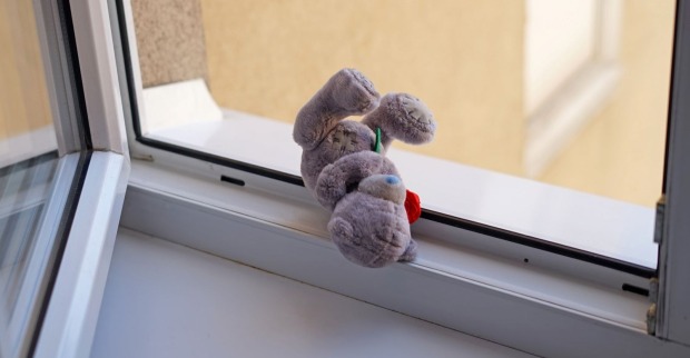 Ein kleiner Teddybär vor einem offenen Fenster.