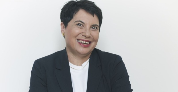 lächelnde Frau mit kurzen schwarzen Haaren, weißem Shirt und schwarzem Blazer