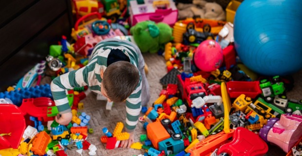 Kind spielt mit Babyausstattung und Spielzeug in einem Kinderzimmer