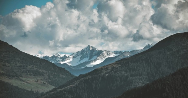 Berglandschaft in Tirol mit schneebedeckten Gipfeln und bewaldeten Hängen als Symbolbild für den schweren Wanderunfall in Westendorf, bei dem ein 20-Jähriger 85 Meter abstürzte.