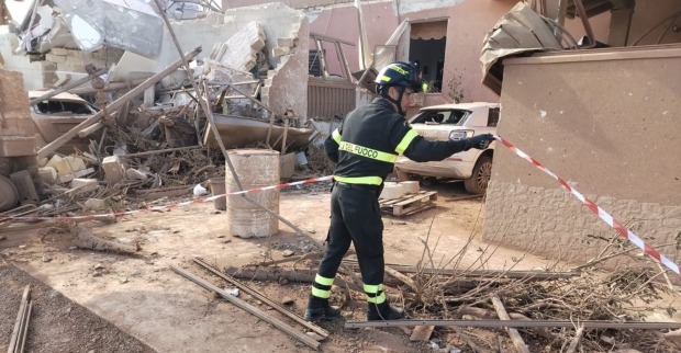 Italienischer Feuerwehrmann zwischen Trümmern und beschädigten Gebäuden nach einem schweren Unwetter, Sizilien