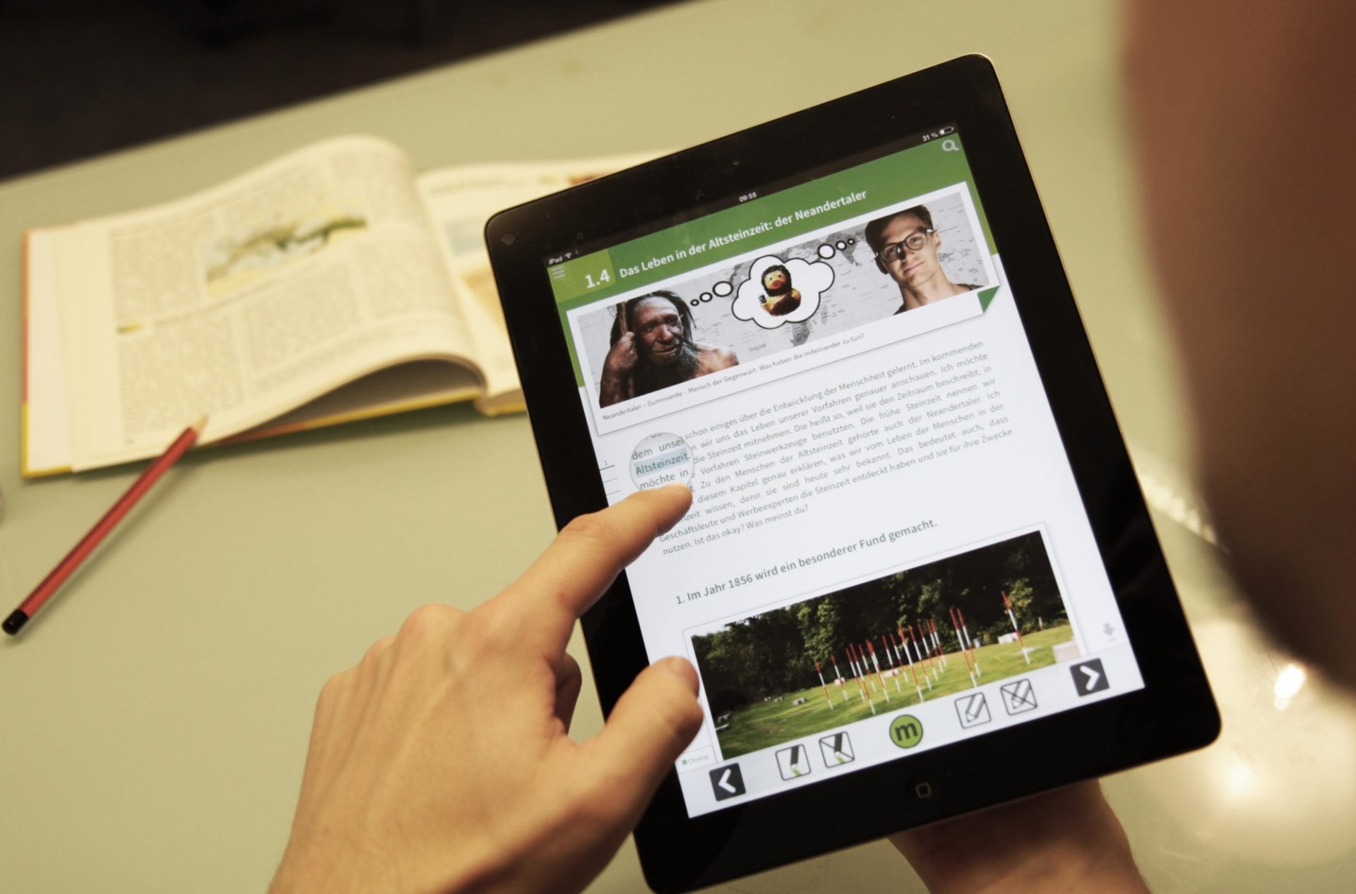 Eine Person lernt digital mit einem Tablet, zu sehen ist ein Kapitel zu dem Thema Steinzeit.