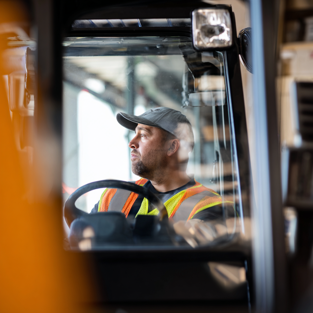 Cursist volgt heftruckopleiding bij Heftruckconcurrent om een heftruckcertificaat te behalen, met uitleg over de kosten en verschillende opleidingsopties in een magazijnomgeving.