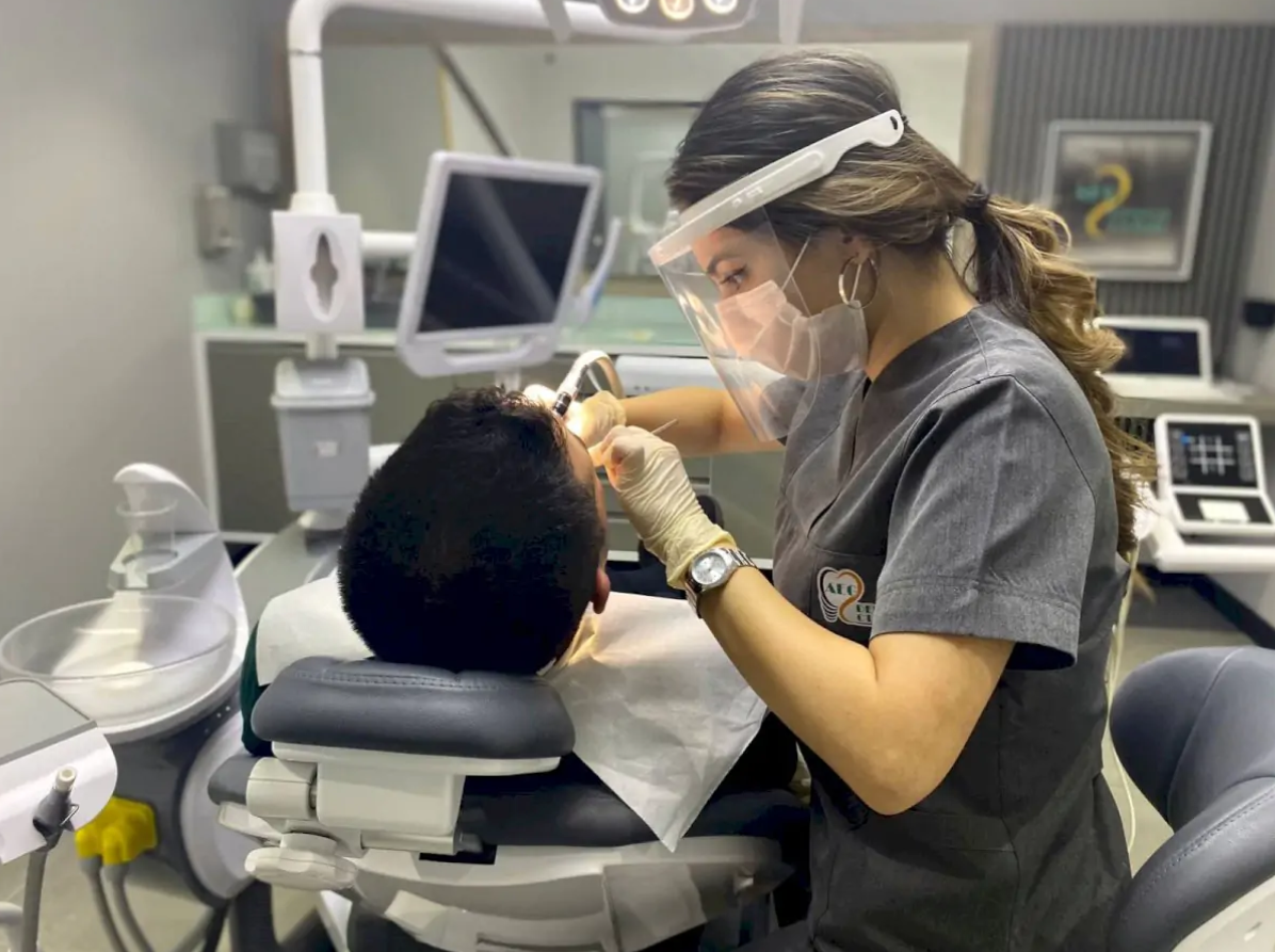 El médico coloca implantes dentales en cada mandíbula para cambiar total la sonrisa del paciente