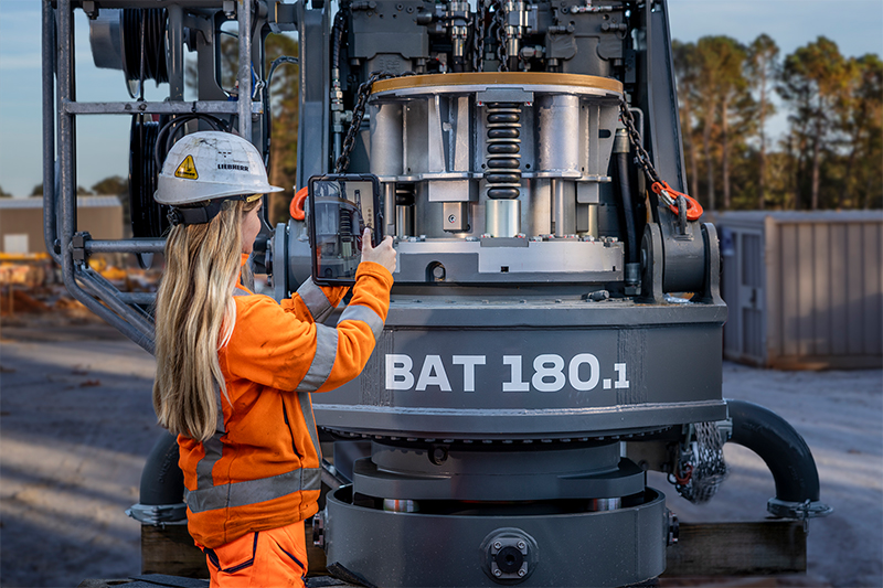 Frau mit device vor Baumaschine