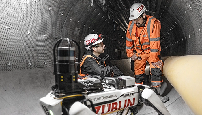Roboterhund mit zwei Arbeitern im Tunnel