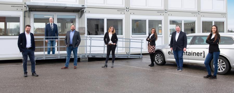 Leute stehen vor einem Containerdorf