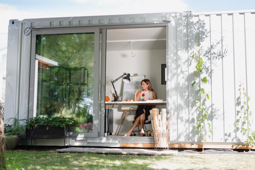Frau sitzt im Home office im Container