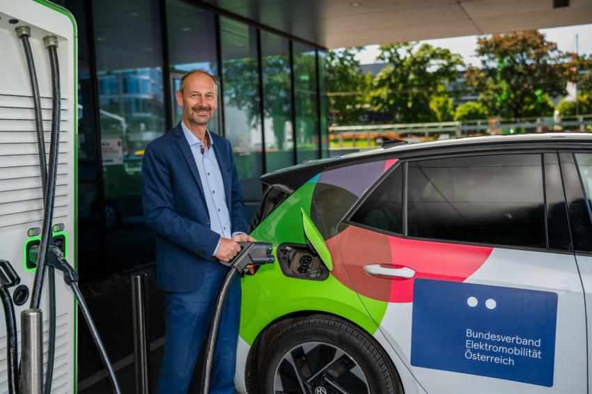 Mann steht an einer E-Tankstelle und will sein Auto laden.