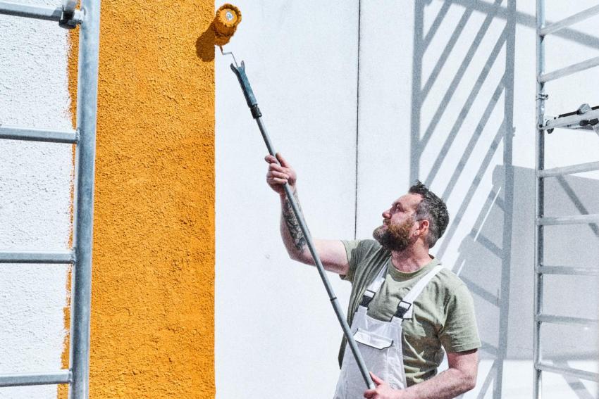 Mann malt Fassade