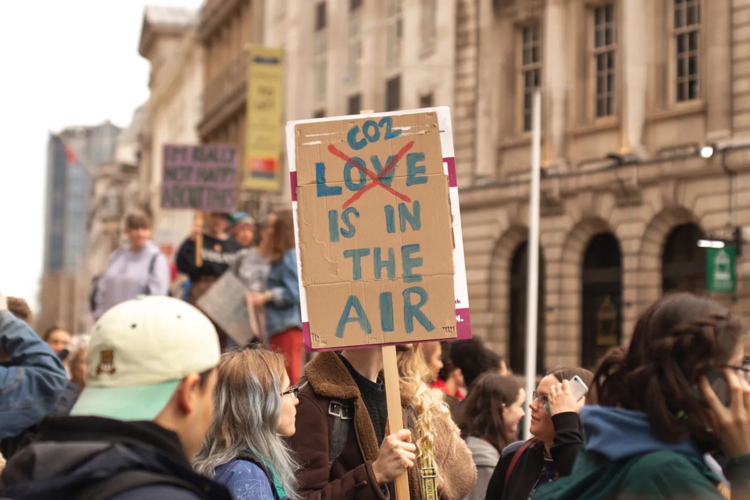 Protester holds a sign reading “CO2 is in the air,” with “LOVE” crossed out, during a city climate march