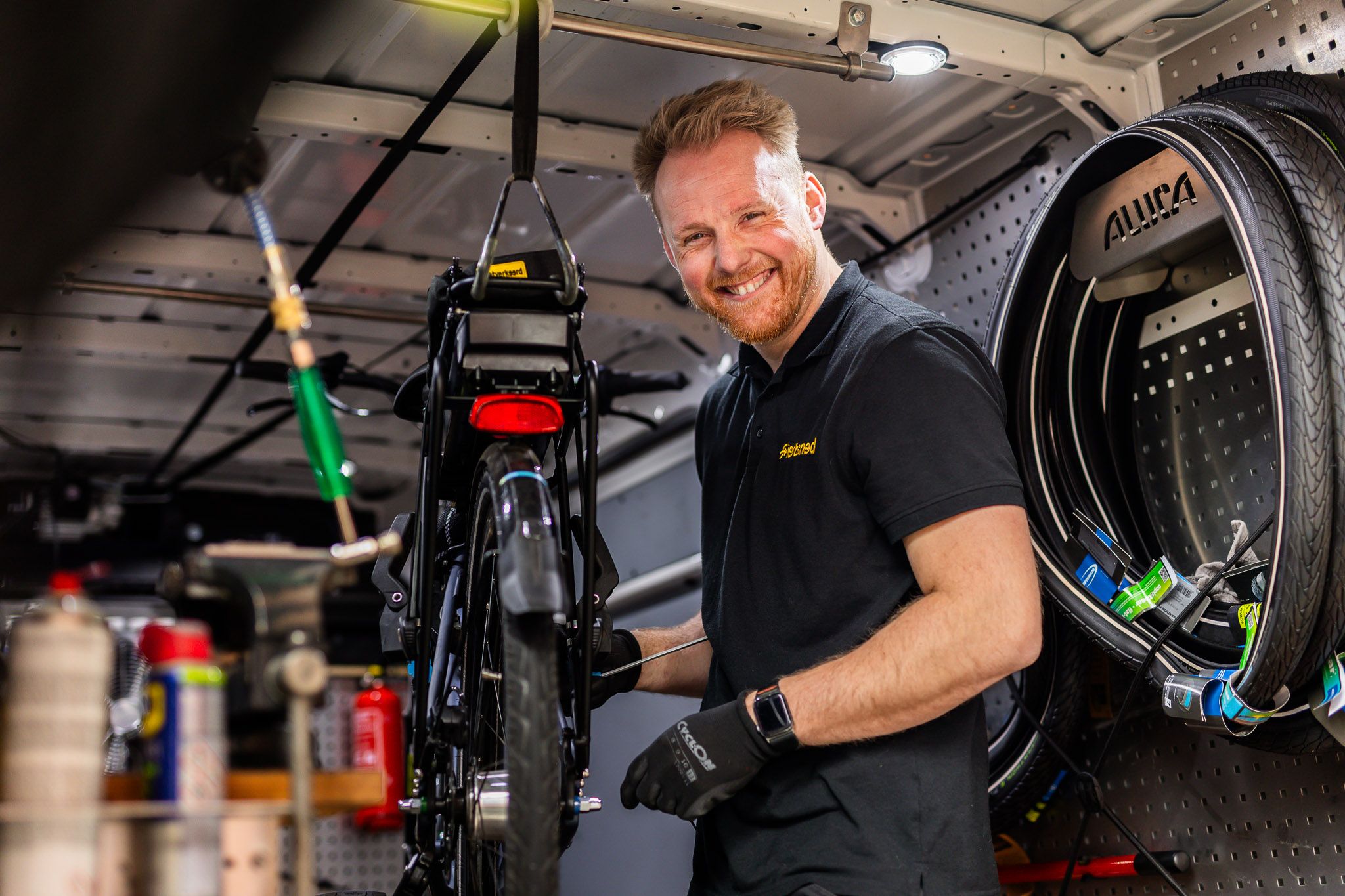 Lachende monteur die in een bus aan een fiets sleutelt.