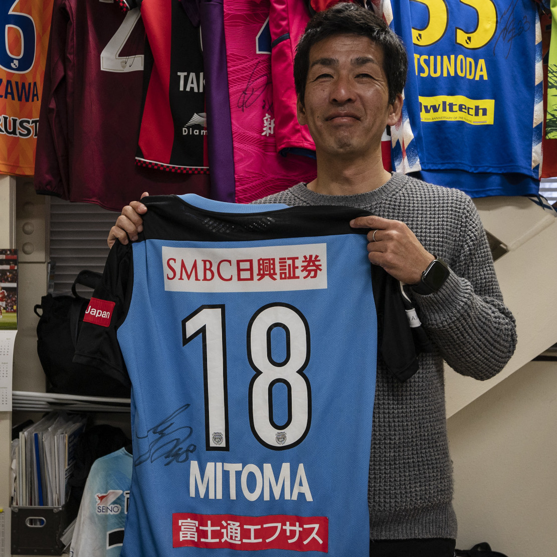 Masaaki Koido posing with Mitoma's old jersey (©AFP)
