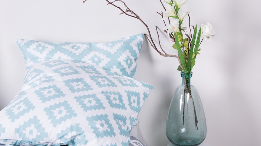 Zwei gemusterte Kissen mit einer Blumenvase