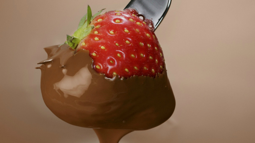 chocoladefondue gesmolten chocolade op rode aardbei vork groen kroontje