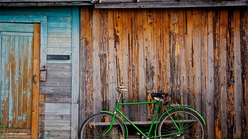 fietsaccessoires kind groene fiets tegen houten muur