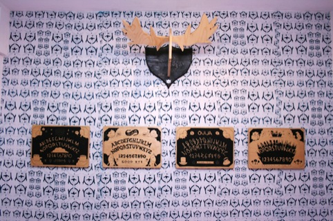 A selection of ouija boards and a mock hunter's trophy by Kid Acne