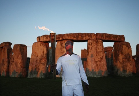 Olympic gold medalist former sprinter Torchbearer 001 Michael Johnson holds the Olympic Flame at Stonehenge at the beginning of Day 55 of the London 2012 Olympic Torch Relay