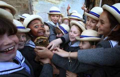 Schoolgirls from Leadenhall School, Salisbury, hold the Olympic Torch of Olympic gold medalist former sprinter Torchbearer 001 Michael Johnson at Salisbury Cathedral during Day 55 of the London 2012 Olympic Torch Relay.