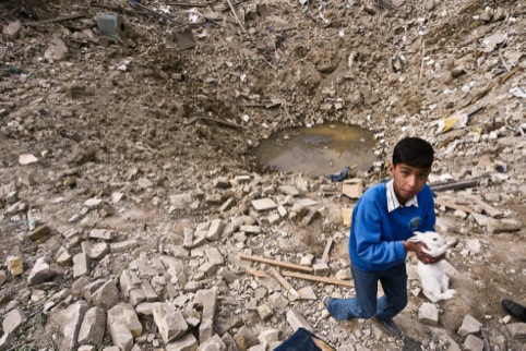 A child recovers a pet rabbit from his bombed neighbourhood, Baghdad, 2003.