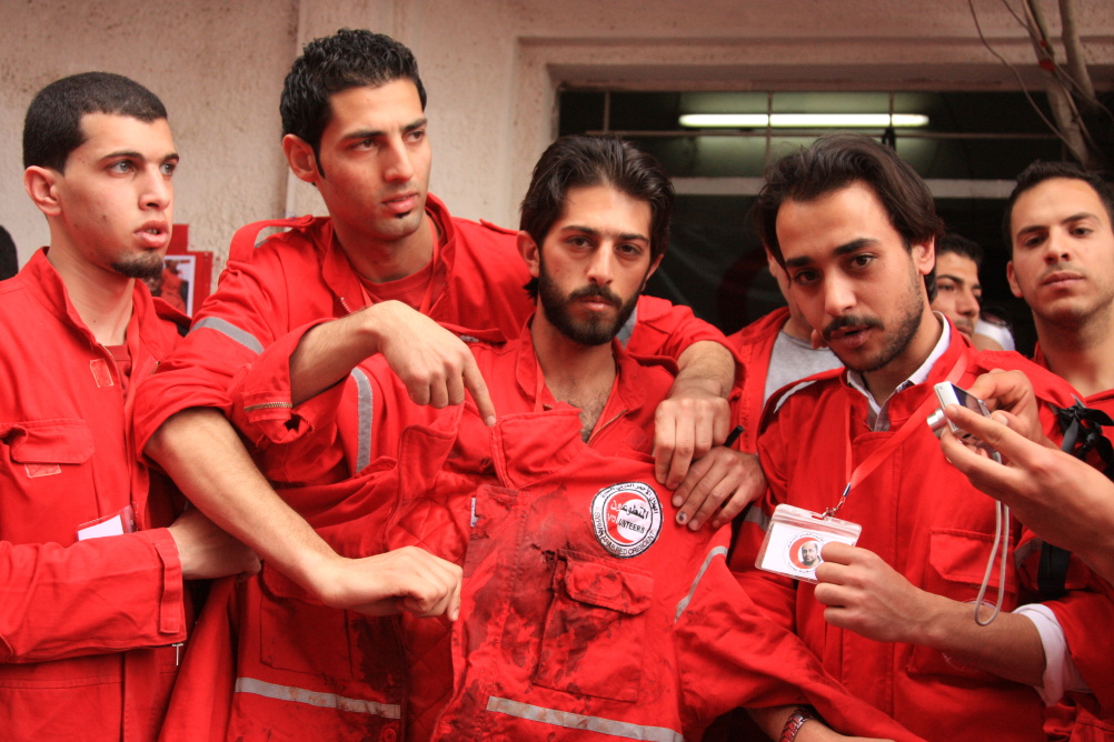 Syria: Humanity in Conflict at IWM North. SARC volunteers hold up the jacket of Mohammad Al-Khadra, a SARC volunteer who died on the 24 April 2013, while on duty in an ambulance on an emergency call. 30 April 2012.