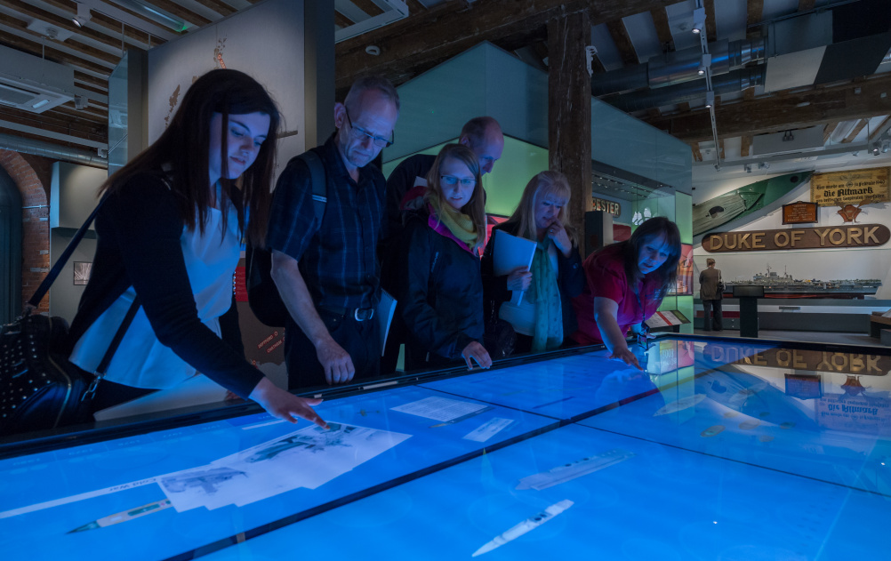 HMS Hear My Story - Blue Timeline table - view towards Artefact Wall 