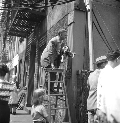 Frame from a contact sheet featuring the photojournalist Weegee seeking a better angle from a stepladder, during the filming of Jules Dassin’s film The Naked City, July 1947, New York City. Kubrick would hire Weegee 15 years later as a set photographer fo